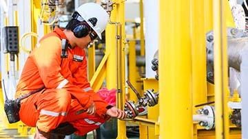 Person wearing orange coveralls and white hardhat